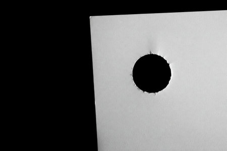 White paper with a round hole on a black background. Space for textの素材