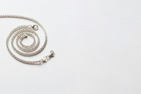 A silver chain laid in a spiral on a light background. Space for textの素材