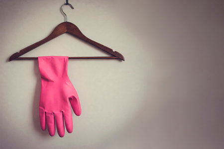 A pink glove hangs on a wooden hanger. Space for textの素材
