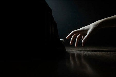 A hand reaches for an unknown object in the dark. Space for textの素材