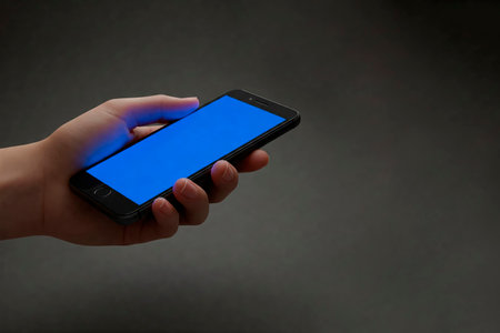 A smartphone with a blue screen in your hand. Space for textの素材