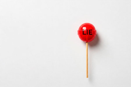 A red lollipop with LIE written on a light background. Space for textの素材
