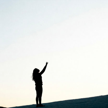 A girl on a slope stretches her hands to the sky at dawnの素材