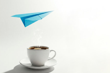 A blue paper airplane hovers over a cup of hot coffee. Space for textの素材