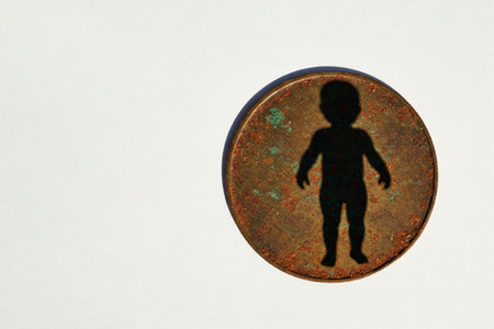 Coin with the shadow of a child's silhouette on a light background. Space for textの素材