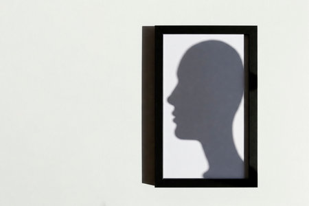 Shadow of the head in profile in a frame on a light wall. Space for textの素材