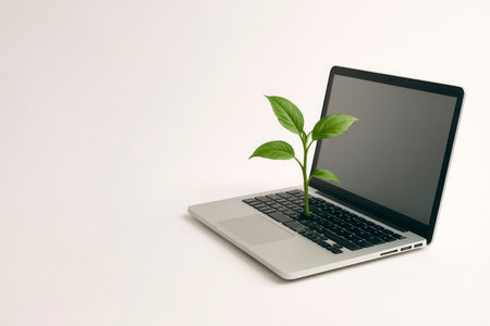 A green sprout makes its way through the keys of the laptop. Space for textの素材