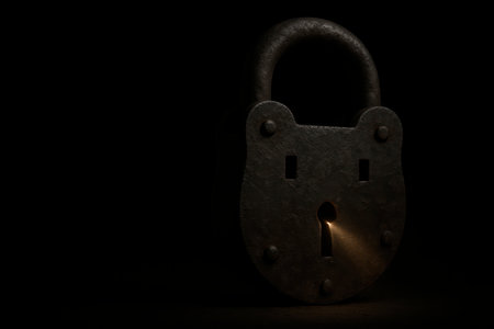 An old rusty lock with a golden ray of light from a keyhole. Space for textの素材