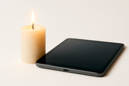 Candle and tablet on a light background. Space for textの素材