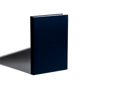 A dark book stands vertically on a light background. Space for textの素材
