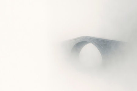 A stone bridge disappearing in a thick fog against a light background. Space for textの素材