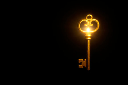 An antique gold key with a backlight on a black background. Space for textの素材