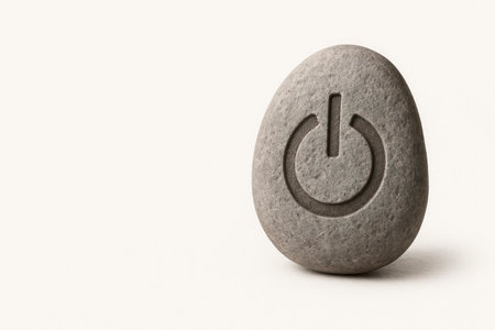 Stone with engraving of the power button on a light background. Space for textの素材