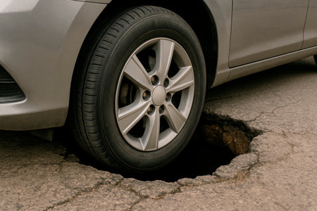 The wheel of the car got stuck in a deep hole in the roadの素材