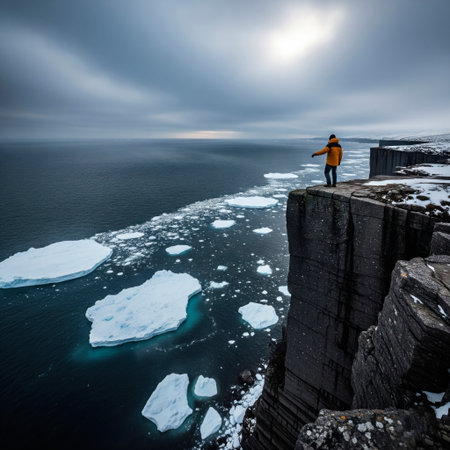 A man in a yellow jacket stands on the edge of an Arctic cliffの素材