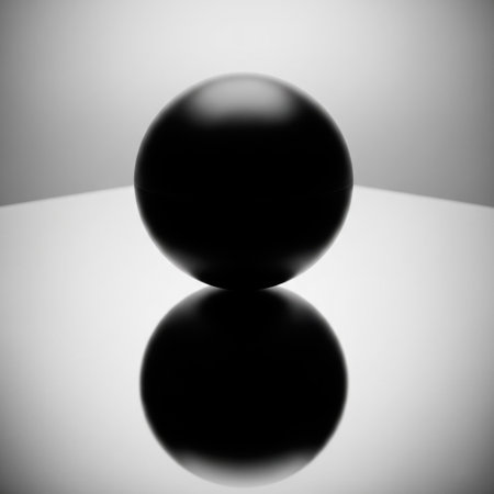 A black ball on a light surface with a reflectionの素材