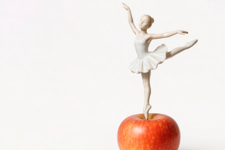 A porcelain ballerina stands on a red apple. Space for textの素材