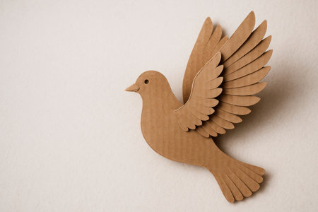 A cardboard pigeon with spread wings on a light background. Space for textの素材