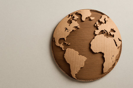 Cardboard globe with continents cut out on a light background. Space for textの素材