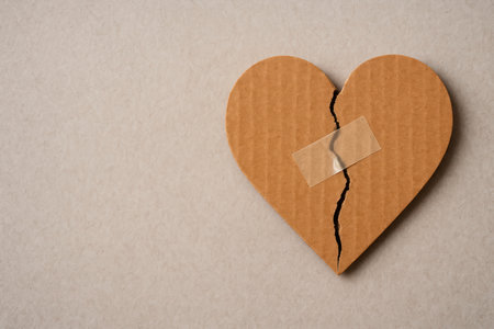 A cardboard heart with a crack sealed with tape. Space for textの素材
