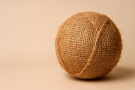 A ball made of rough burlap on a neutral beige background. Space for textの素材