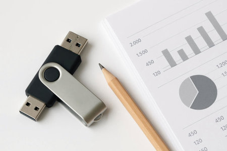 Two flash drives, a pencil and a business graph on a white backgroundの素材