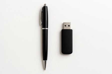 A black pen and a flash drive on a light background. Space for textの素材