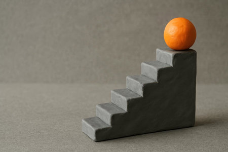 A gray ladder made of plasticine with an orange ball. Space for textの素材