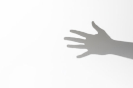 Shadow of an outstretched arm on a white background. Space for textの素材