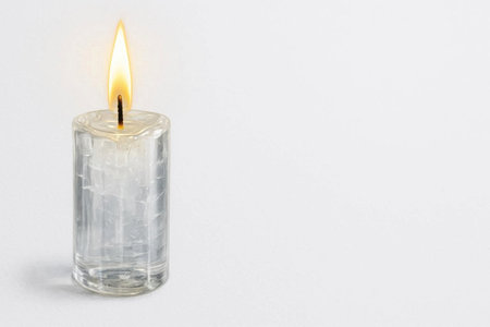 A burning candle in a transparent glass cylinder. Space for textの素材