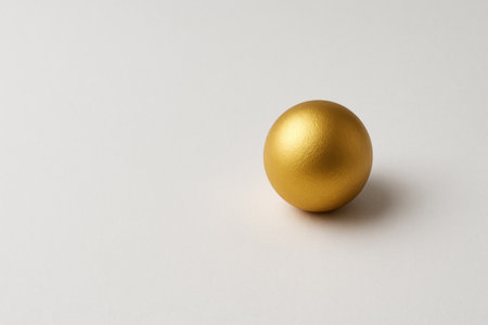 Golden ball on a light minimalist background. Space for textの素材