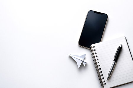 A phone, a notebook and a paper airplane on a white background. Space for textの素材