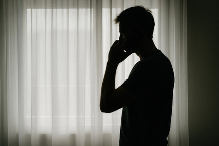 Silhouette of a man at the window talking on the phone. Space for textの素材