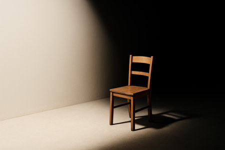 A lonely wooden chair in a beam of light. Space for textの素材