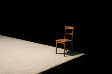 A lonely wooden chair in a bright light in the darkness. Space for textの素材
