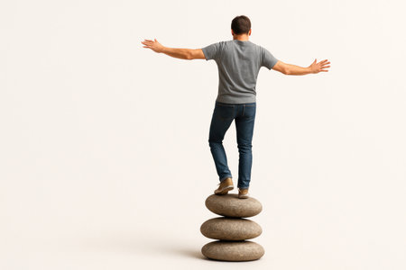 A person stands on a pile of smooth stones in an attempt to keep his balance. Space for textの素材