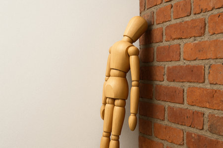 A wooden mannequin resting its head on a brick wall. Space for textの素材