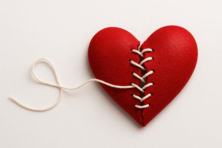 A red heart sewn with white thread. Space for textの素材