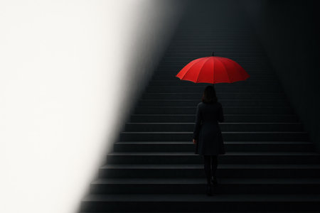 A woman with a red umbrella climbs a dark staircase to the light. Space for textの素材