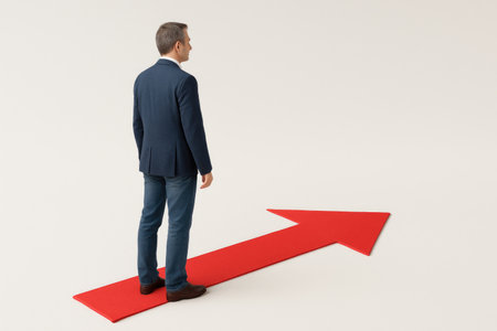 A businessman stands on a red arrow pointing forward. Space for textの素材