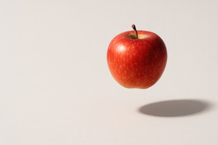 A red apple floats in the air on a light background. Space for textの素材