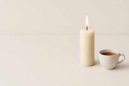Burning candle and cup of tea on a minimalist background. Space for textの素材