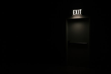 A lit exit door in complete darkness. Space for textの素材