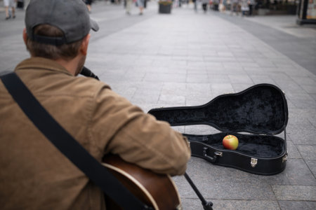 A street musician, a guitar case, an apple insideの素材
