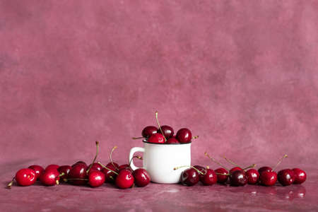 Fresh summer berries in a white cup. Cherry background. Summer fruits and food concept. With Copy...