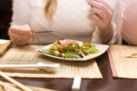 Woman eating salad in japanese restaurant. Focus on dishの写真素材