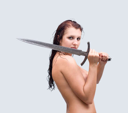 Attractive  woman with wet hair take sword on gray backgroundの写真素材