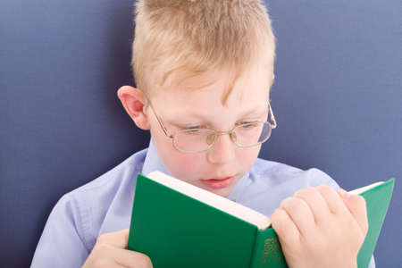 Boy in eyeglasses reading interesting book