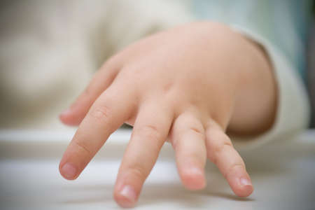 Baby's hand touching the table. Very shallow depth of field. Focus on center of fingersの写真素材