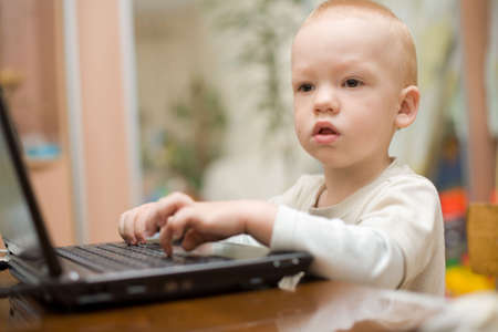 Little boy typing text on laptop at home. Shallow depth of field. Focus on eyes